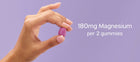 Hand holding a purple gummy with text about magnesium content on a purple background
